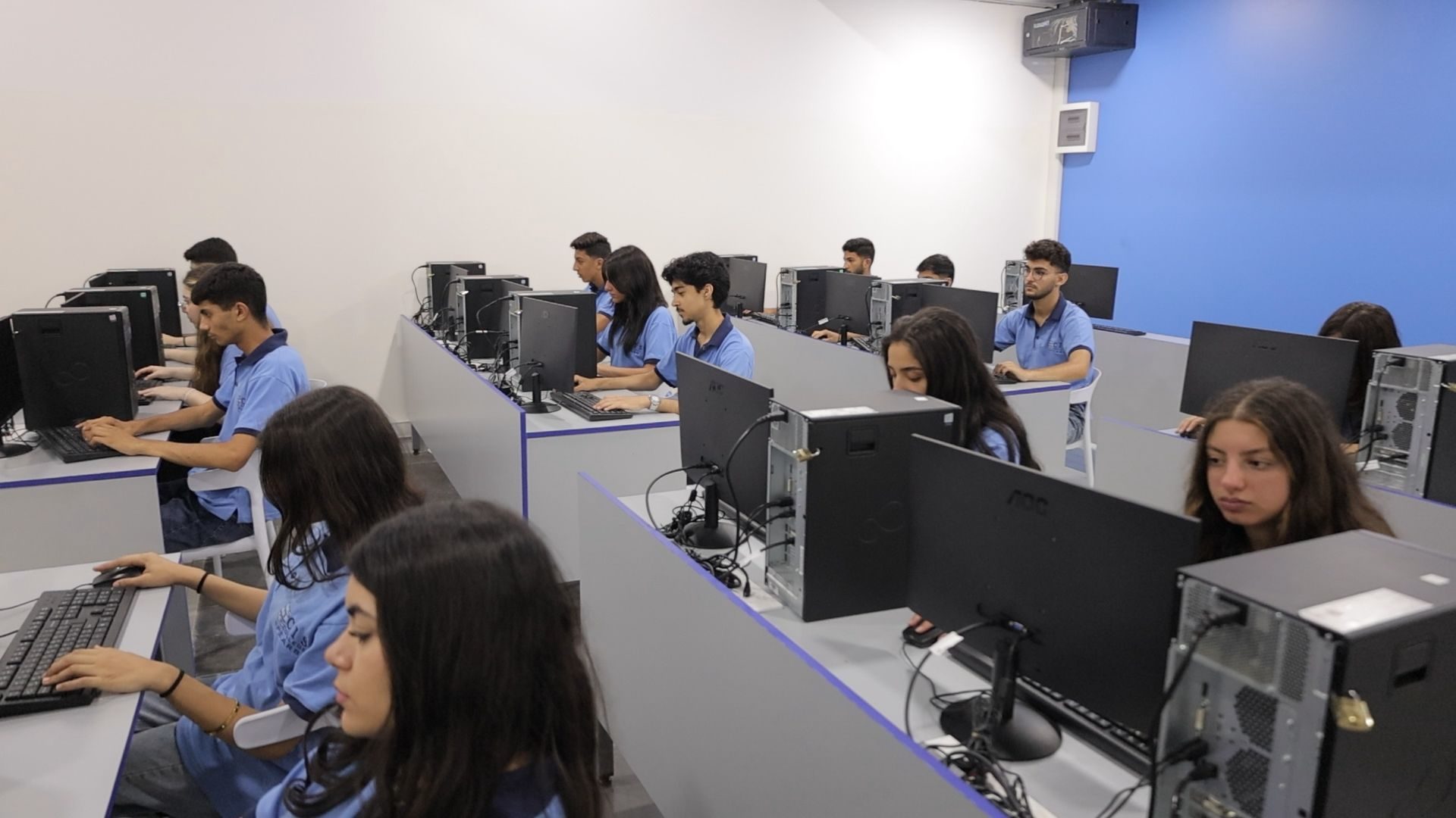 Multiple students working at desktop computer workstations in modern computer lab classroom