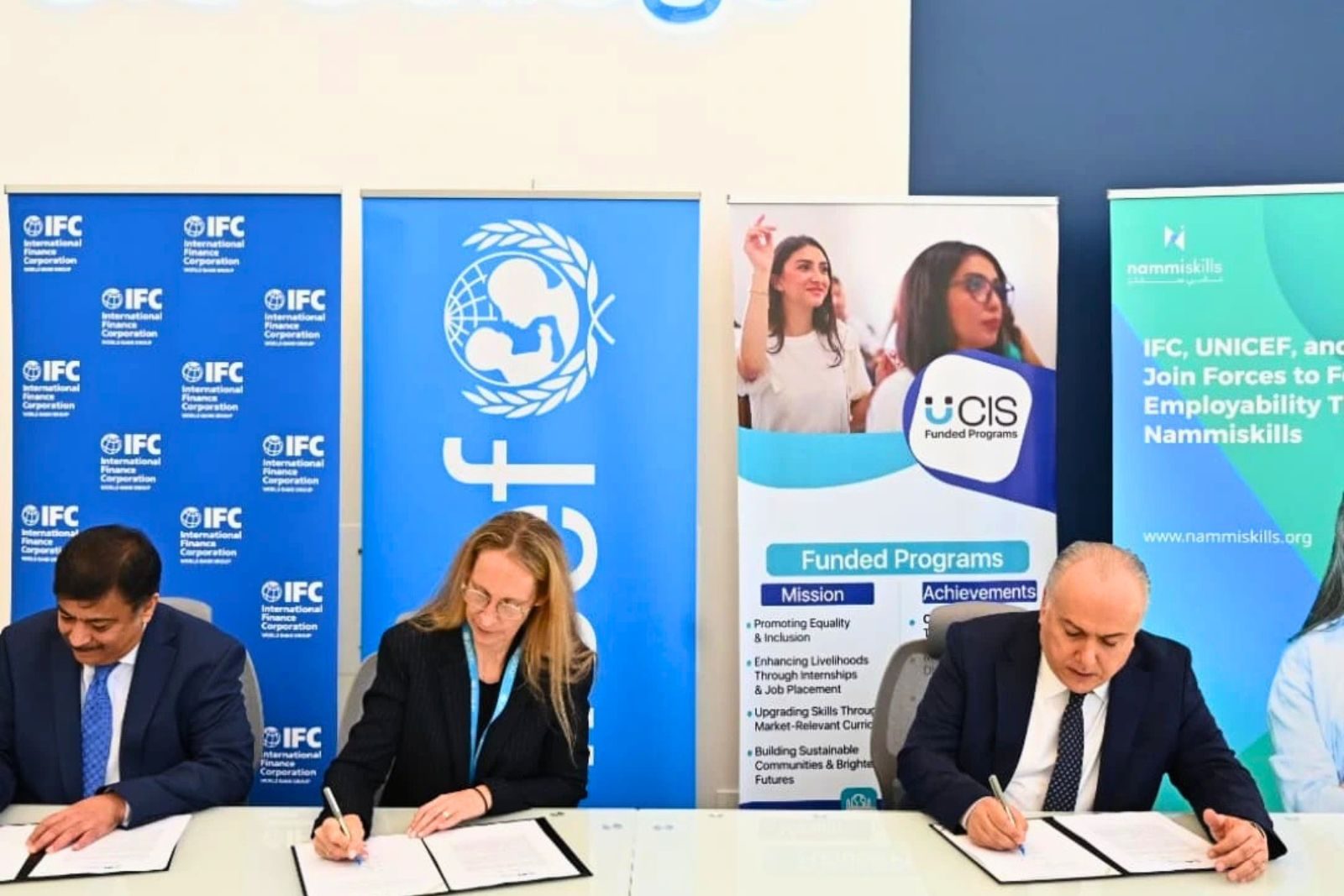 Professional signing ceremony with international organization banners